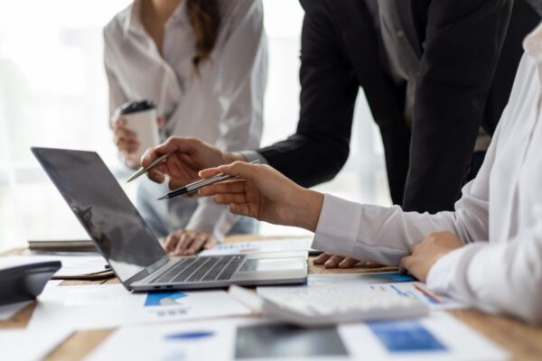 Na zdjęciu widoczne są osoby współpracujące przy laptopie oferujące usługi rachunkowe.