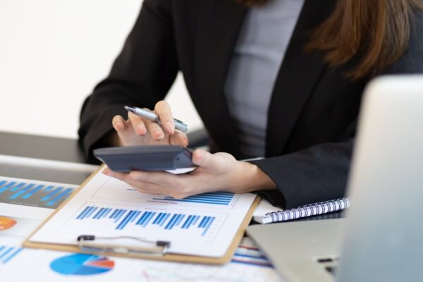 Doradczyni księgowa używa kalkulatora, analizując wykresy finansowe.