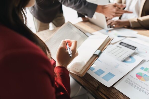Osoby pracujące nad dokumentami i analizami w biurze księgowym.